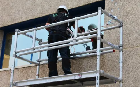 Técnico trabajando en un andamio, revisando las partes de un andamio para asegurar su estabilidad.