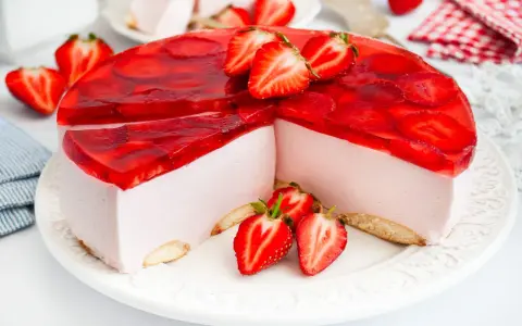 Pyszny sernik na zimno z mascarpone, udekorowany galaretką i świeżymi truskawkami. Idealny na letnie popołudnie.