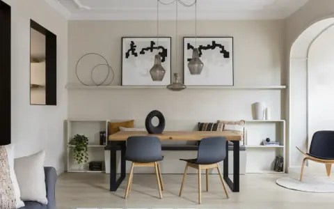 Comedor moderno con paredes color beige arena, mesa de madera, sillas grises y arte abstracto.