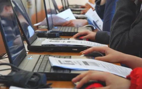 Uczniowie klasy 4 na lekcji informatyki pracują przy komputerach, korzystając z myszek i dokumentów.
