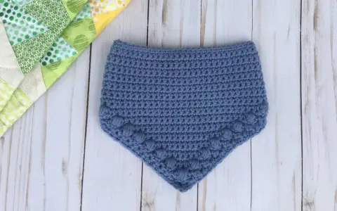 Babero azul tejido a crochet con detalle de pompones. Patrones baberos crochet instrucciones para crear esta linda prenda.