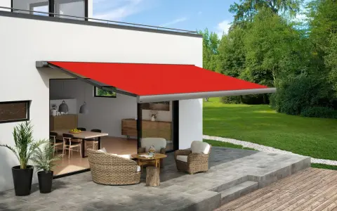 Toldo rojo extendido sobre un patio con muebles de mimbre, ofreciendo ideas para dar sombra en un patio.