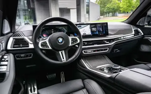 Wnętrze BMW x7: skórzana tapicerka, nowoczesny kokpit z dwoma ekranami i sportowa kierownica.