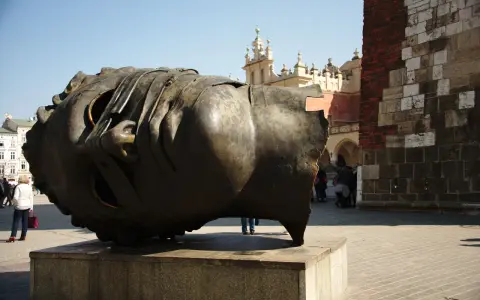 Ogromna, metalowa rzeźba głowy Igora Mitoraja na placu w Krakowie.