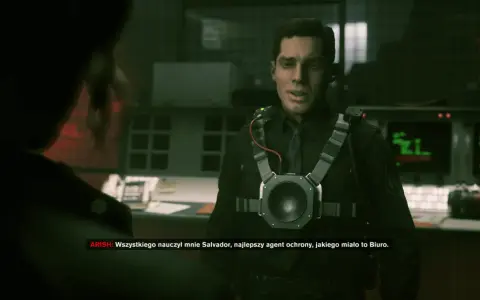 Agent w czarnym mundurze z urządzeniem na piersi, słucha kogoś. W tle monitory. To moment, gdy kontrol czas gry jest kluczowy.