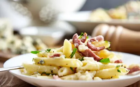 Piatto di pasta porri e salsiccia, cremoso e saporito, con pezzetti di formaggio e erbe fresche.