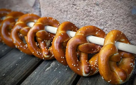 Frisch gebackene Brezeln, perfekt für ein Laugengebäck Rezept. Mit grobem Salz bestreut, liegen sie auf Holzbrettern.