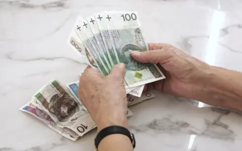 Dłonie liczą banknoty 100 zł. Zastanawiasz się, jaka emerytura z KRUS po 10 latach?