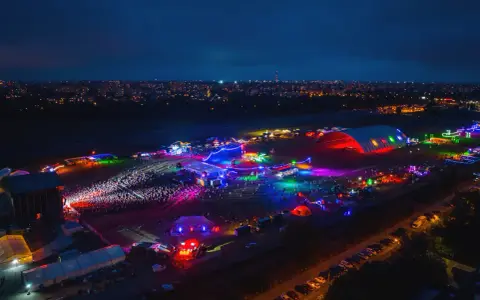 Nocne, kolorowe światła rozświetlają teren festiwalu na powietrzu. Tłumy bawią się pod wielkim, podświetlonym namiotem i na otwartych scenach.