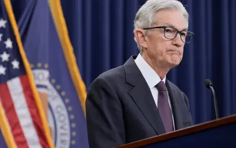 Jerome Powell przemawia na tle flag USA i Rezerwy Federalnej, instytucji, która budzi pytania, czy fed jest prywatny.