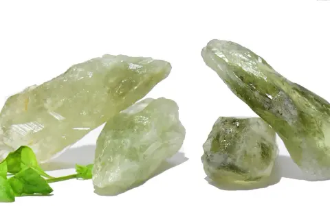 Cristalli grezzi di ametista verde, noti per il loro significato di crescita e rinnovamento, su sfondo bianco con foglie verdi.