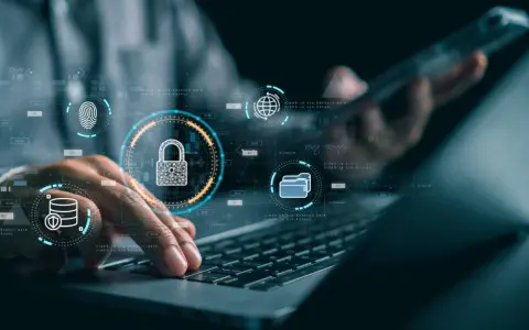 Manos sobre teclado de laptop, con iconos de seguridad digital: candado, huella, base de datos, globo terráqueo. Esto ilustra qué es la seguridad informática.