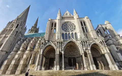 The magnificent Chartres Cathedral, with its iconic rose window and soaring spires, stands majestically against a clear blue sky.