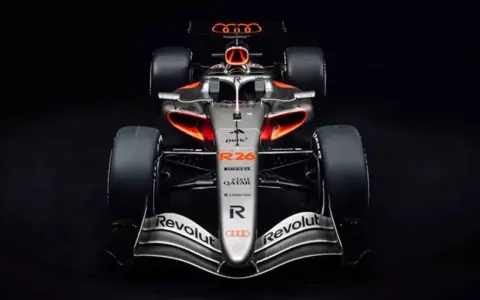 El coche de audi f1, plateado con detalles naranjas y negros, listo para la competición.