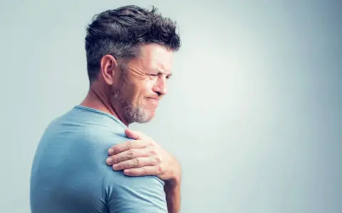 Homme souffrant de douleurs articulaires à l'épaule, possiblement liées à une carence en vitamine B12.