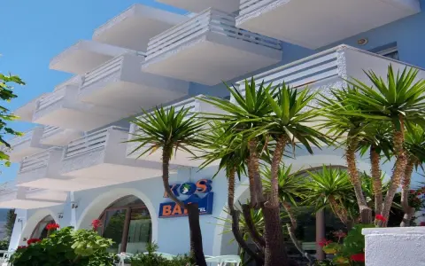 Hotel na Krecie z białymi balkonami i palmami.
