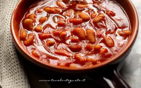 Un primo piano di fagioli all'uccelletto in una ciotola di terracotta, un classico delle ricette italiane.