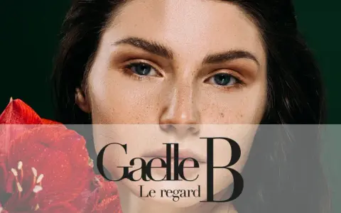 Un visage de femme avec des taches de rousseur naturelles, tenant une fleur rouge. Le regard est intense.