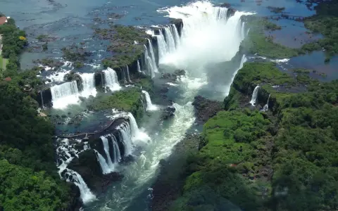 An aerial view of Iguazu Falls, a breathtaking cascade of water surrounded by lush green jungle. A perfect destination for 2 days of unforgettable adventure.