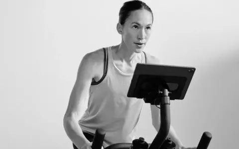 Focused woman powering through a hiit cycle workout on a stationary bike, her muscles engaged.