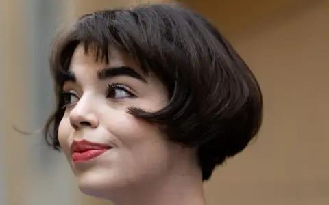 Ein kurzer Bob mit leichten Wellen, der ihr Gesicht umrahmt. Perfekt gestylt für einen mühelosen Look.