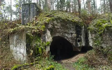 Ruiny twierdzy Osowiec, porośnięte mchem i liśćmi, zapraszają na zwiedzanie. Wejście do bunkra w lesie.
