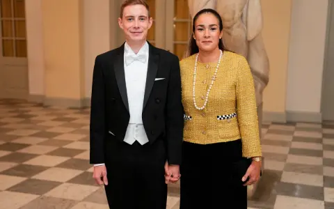 Jonas Vingegaard and his wife, Trine Marie, dressed formally for an event. He wears a tuxedo, and she sports a yellow tweed jacket and pearl necklace.