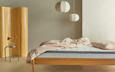Una habitación nórdica con cama de madera, ropa de cama rosa y un biombo de bambú.