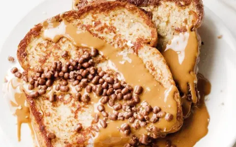 Tostadas francesas cubiertas con crema de cacahuete y crujientes bolitas de chocolate. Un desayuno delicioso y tentador.