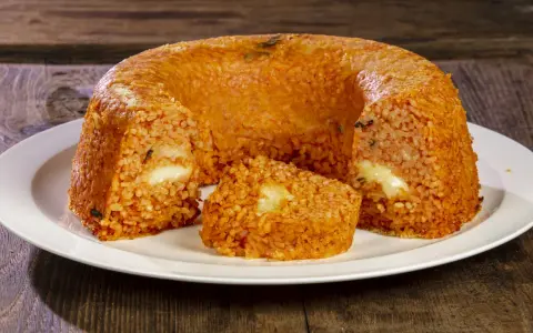 Un invitante timballo di riso, dorato e ripieno di formaggio filante, pronto per essere gustato.