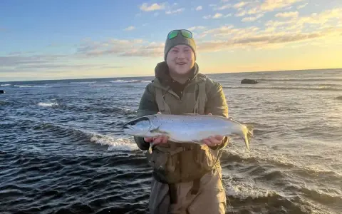 Glad fiskare med en fin öring vid havet, en lyckad dag med **trout fishing** i Sverige.