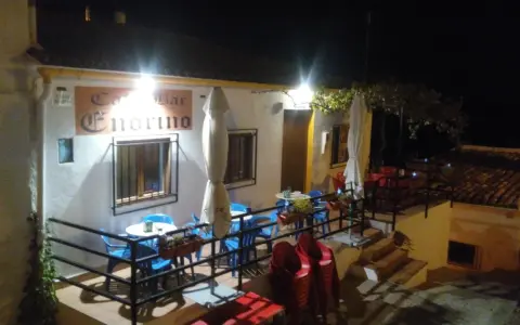 Bar Endrino, un lugar acogedor donde comer en Segura de la Sierra. Mesas y sillas azules y rojas esperan bajo luces cálidas.
