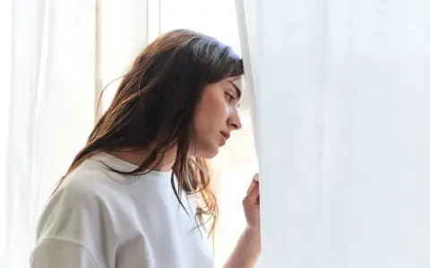 Młoda kobieta zamyślona, oparta o zasłonę. Czy to melancholia co to?