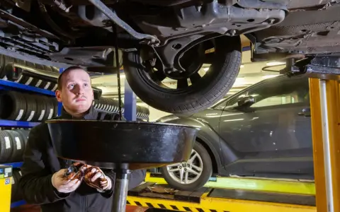 Mechanik spuszcza zużyty olej z samochodu. Zastanawiasz się, ile trwa wymiana oleju i filtrów?