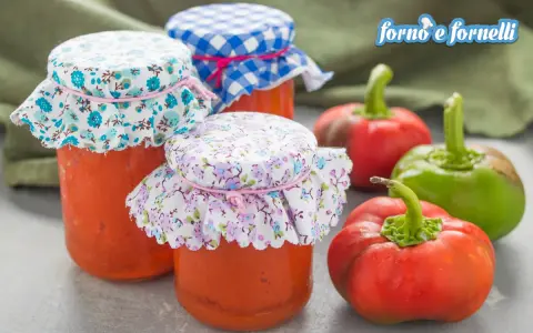 Barattoli di crema di peperoni fatti in casa, con peperoni freschi sullo sfondo.