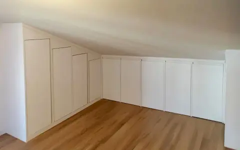 Armadi su misura sfruttano ogni centimetro, perfette idee sottotetto molto basso. Pavimento in legno chiaro.
