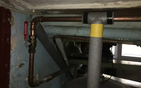 Kopparrör med isolering och en röd ventil, redo att fylla på luft i hydrofor.