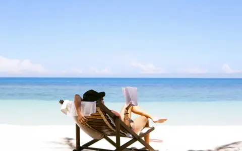 Person entspannt sich lesend am Strand. Ein Traum für jeden Praktikanten, der seinen Urlaubsanspruch genießt.