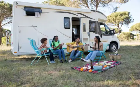 Eine Familie genießt das Camping mit Musik und Picknick vor ihrem Wohnmobil.