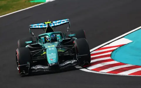 El coche Aston Martin F1, con el número 14, acelera en una curva.