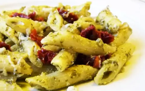 Penne z pesto i kawałkami suszonych pomidorów, posypane parmezanem. Pyszne danie, które zachwyci każdego miłośnika makaronu z suszonymi pomidorami.