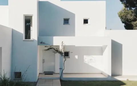 Fachada blanca moderna con sombras marcadas. La mejor pintura para fachadas exteriores protege y embellece esta arquitectura minimalista.