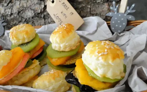 Mini burgery z ciasta francuskiego z owocami: kiwi, mango, brzoskwinia i różowa wędlina. Wyglądają jak małe dzieła sztuki.