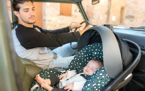 Padre atento conduce mientras su bebé duerme plácidamente en su silla de auto, listo para viajar con bebes.