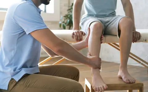 Un podologue examine la jambe d'un patient, un examen essentiel pour la podologie.