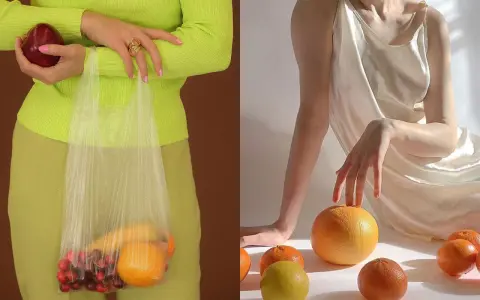 Mani che tengono una mela e una busta con ciliegie e arance. Altre arance e un limone sparsi su uno sfondo chiaro, evocando un'essenza di fruit extract.