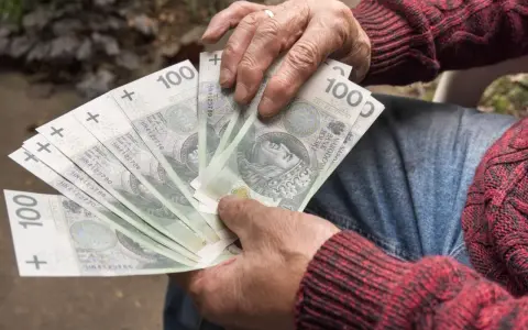 Dłoń trzyma wachlarz banknotów 100 zł. Czy to uczciwy zarobek, czy szalbierstwo?