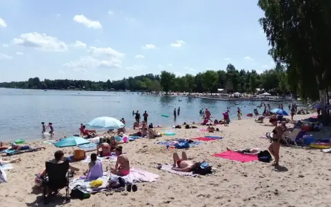 Słoneczny dzień nad zalewem Sosina. Ludzie odpoczywają na plaży, kąpią się i opalają.