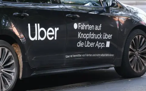 Schwarzes Auto mit "Uber" Logo. Hier erfährst du, wie kann man über Fahrer werden und Fahrten über die App buchen.