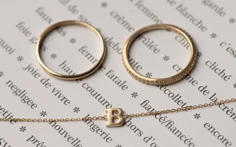 Anelli e collana in oro 14 carati, che significa un gioiello di qualità, su pagine di un libro con parole francesi.
